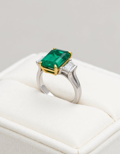 &quot;Abigail&quot; White and yellow gold three-stone ring with an emerald-cut Green emerald center and trapezoid diamond side stones.
