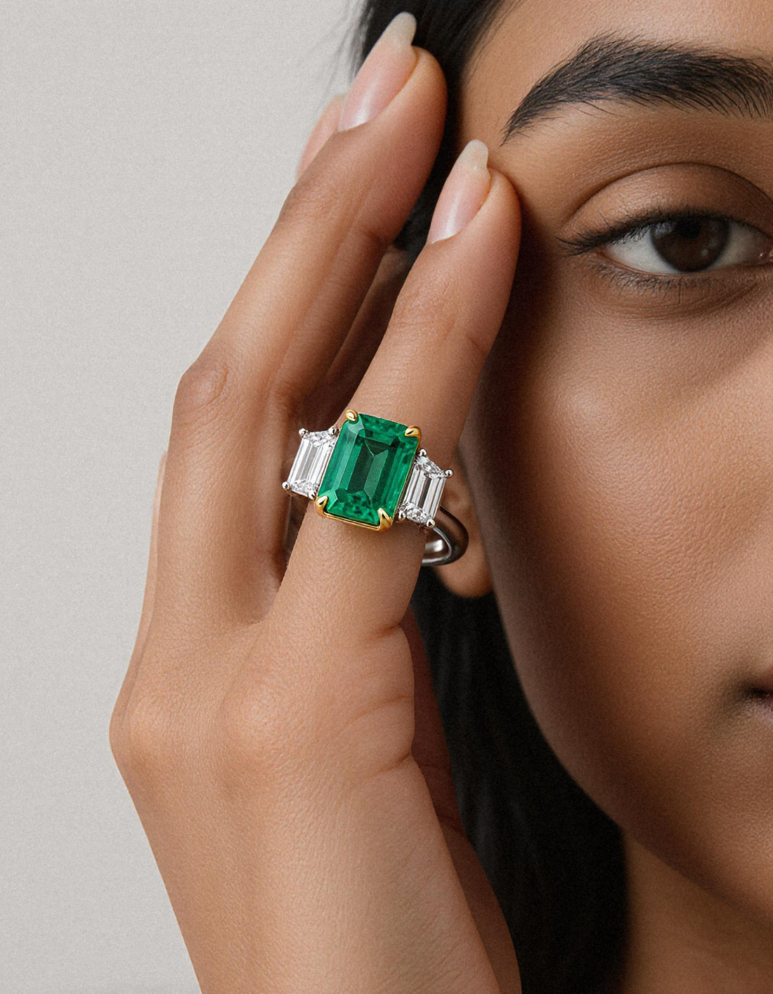 &quot;Abigail&quot; White and yellow gold three-stone ring with an emerald-cut Green emerald center and trapezoid diamond side stones.