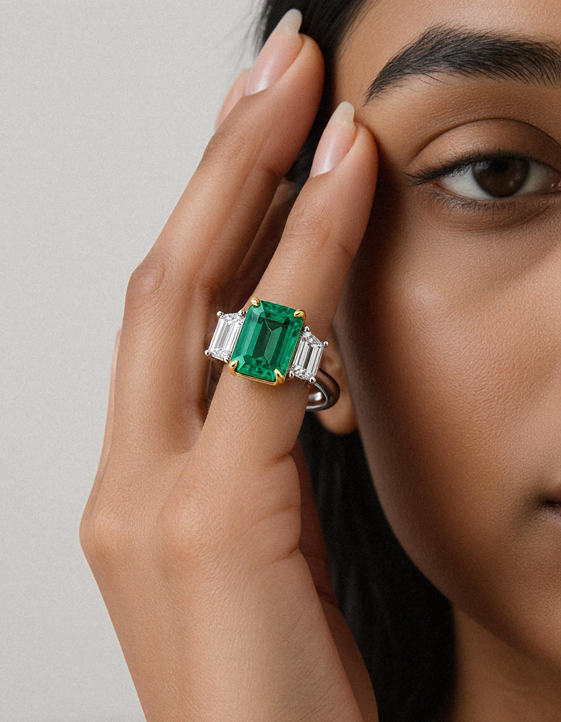 &quot;Abigail&quot; White and yellow gold three-stone ring with an emerald-cut Green emerald center and trapezoid diamond side stones.
