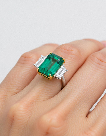 &quot;Abigail&quot; White and yellow gold three-stone ring with an emerald-cut Green emerald center and trapezoid diamond side stones.